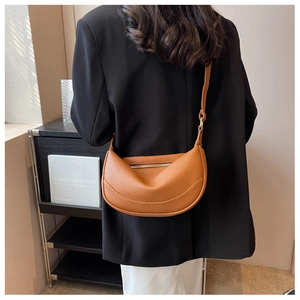 Detail of caramel crescent crossbody bag featuring pebbled texture and adjustable strap