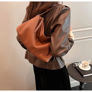 Detail of a brown pleated shoulder bag with a soft hobo shape and smooth zipper closure
