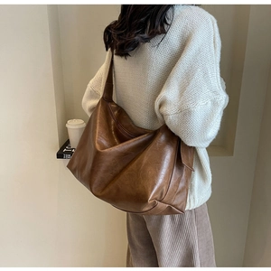 Detailweergave van de grote bruine hobo-tas met getextureerd kunstleer en brede schouderriem