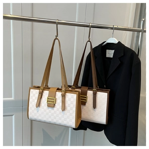 Detail of checkered embossed tote bags with leather handles hanging on a rack