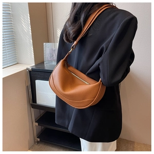 Detail of brown pebbled leather crescent bag with gold zipper and minimalist style