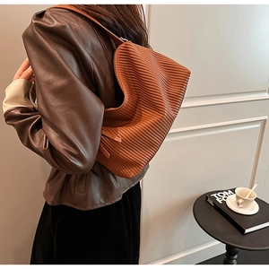 Close-up of a brown pleated hobo bag showing vertical folds and soft faux leather texture