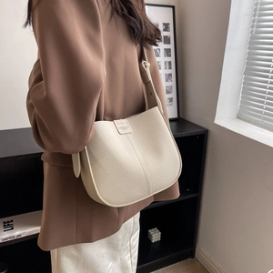 Detail of creamy white pebble grain leather shoulder bag with sleek curved structure