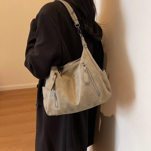 Retro khaki nubuck leather tote bag with silver zippers shown in a lifestyle setting