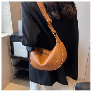 Detailed view of brown litchi textured leather half-moon bag with gold metal buckle