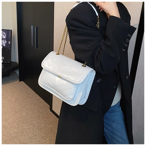 Detail of white quilted leather crossbody bag with elegant gold chain strap on black blazer