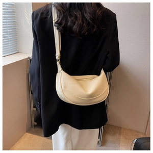 Detail of cream crescent shoulder bag featuring pebbled leather and gold-tone hardware