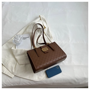 Close-up of brown checkered tote bag with gold buckle on white aesthetic fabric