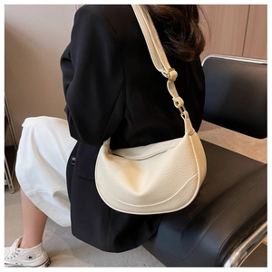 Detail of cream crescent crossbody bag with lychee texture and adjustable strap
