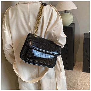 Detail of black V-quilted faux leather bag with elegant gold chain shoulder strap