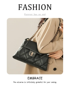 Detail of black quilted leather shoulder bag featuring a gold chain strap and metal lock
