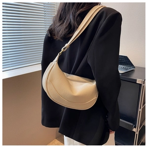 Detail of beige crescent shoulder bag with lychee grain texture and gold hardware details