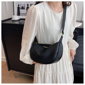 Detail of black pebbled leather crescent bag with adjustable strap and gold zipper
