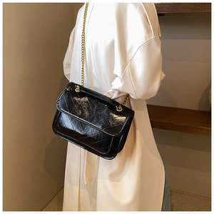 Chic black quilted shoulder bag with gold chain strap shown from a side-view on model