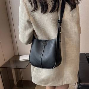 Detail of black lychee grain leather crossbody bag with vertical stitching and strap