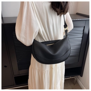 Close-up of black lychee grain crescent bag with gold zippers and adjustable strap