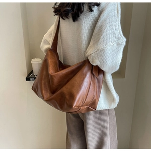Bruine kunstleren hobo tas gestyled met een witte trui en een corduroy broek