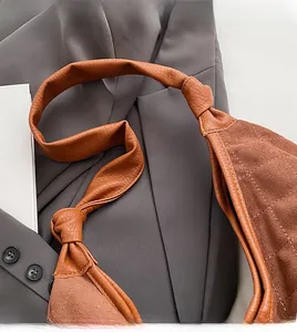 Close-up of brown quilted shoulder bag with unique knotted strap detail and suede texture