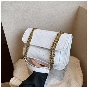Detail of white chevron quilted handbag featuring elegant gold-tone chain strap