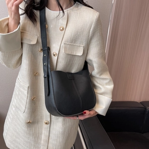 Detail of black lychee grain leather bucket bag featuring adjustable strap and fine stitching