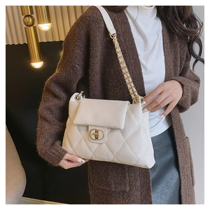 Detail of quilted beige shoulder bag with gold metal clasp and chain strap on model