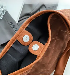 Detailed macro view of brown quilted handbag featuring dual silver magnetic snap closures
