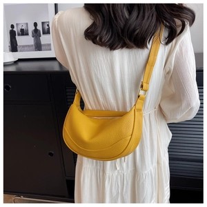 Detail of ginger yellow leather crescent bag with adjustable strap on female model