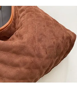 Detail view of brown quilted faux suede texture and leather piping on the shoulder bag