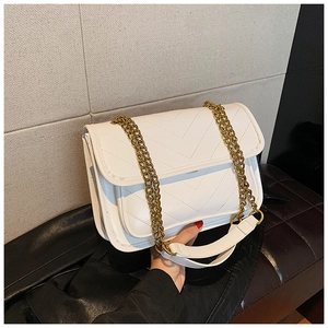 Detail of white chevron quilted bag with gold chain strap held in hand for size context