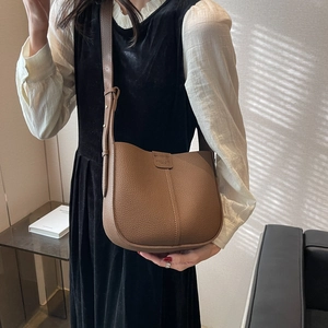 Detail of brown litchi pattern leather crossbody bag with adjustable strap and logo