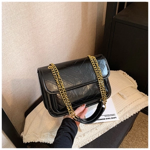 Detail of black chevron quilted leather with elegant gold chain shoulder strap