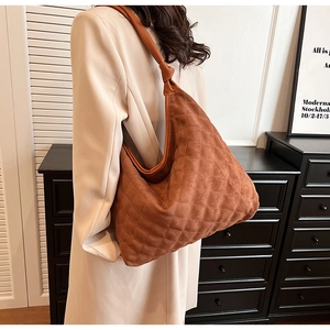 Detail of brown quilted hobo bag featuring soft suede texture and knotted shoulder strap