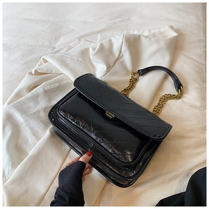 Detail of black chevron quilted leather bag with gold chain strap and lock closure