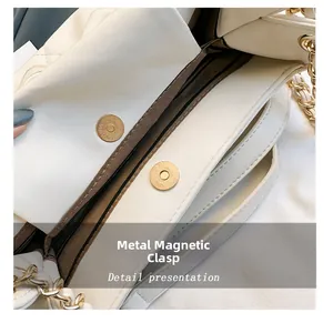 Close-up of golden magnetic hardware buckles and brown fabric lining on a white leather tote