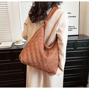 Close-up of brown quilted suede hobo bag with knotted strap and minimalist design