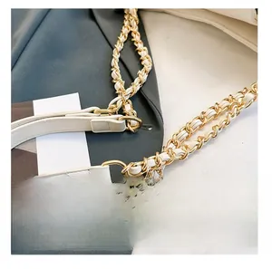 Detail view of premium white leather woven with gold metal chain on a luxury handbag strap
