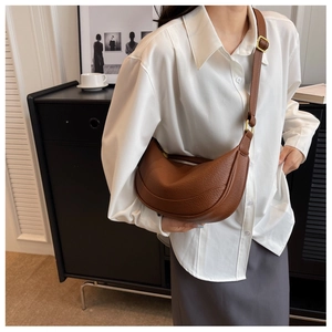 Close-up of brown crescent bag with lychee texture leather and gold metal hardware