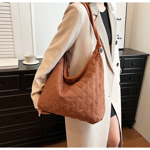 Macro detail of brown quilted suede hobo bag with large capacity and knotted leather strap