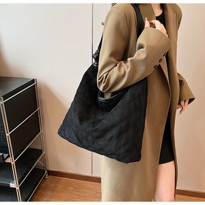 Detail of black quilted large tote bag with fine suede-like texture and leather shoulder strap