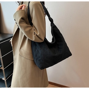 Detail of black quilted hobo bag featuring large capacity and knotted shoulder strap