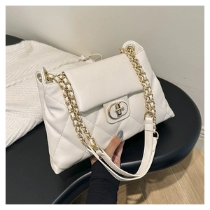 Detail of white quilted tote bag with golden chain strap and sleek metal turn-lock closure