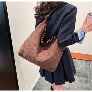 Detail of brown quilted suede shoulder bag with knot strap detail and spacious design