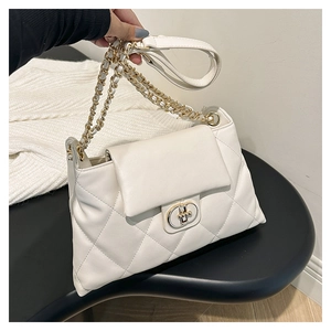 Close-up of white quilted tote bag featuring a golden twist-lock and chain strap