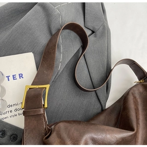 Detail van de donkerbruine vintage tas met textuurafwerking en een gouden vierkante gesp