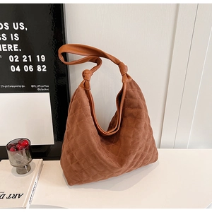 Detail of retro brown quilted hobo bag with suede texture and knotted handle design