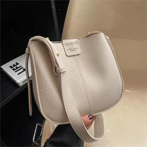 Minimalist beige pebble leather bucket bag for women featuring adjustable shoulder strap