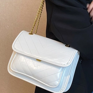 Elegant white chevron quilted chain bag worn by model over a black blazer jacket