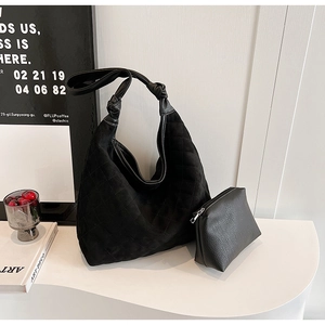 Detail of black quilted hobo bag and matching leather pouch on a stylish white table