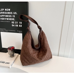 Close-up of brown quilted faux suede tote bag with diamond stitching and knotted strap