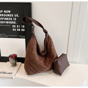 Detail of dark brown quilted suede hobo bag with matching small zipper pouch on white surface